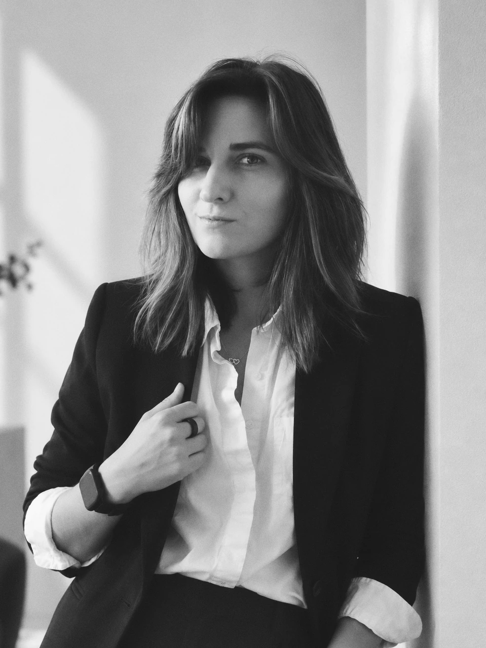Black and white edited portrait of Smyxie in a blazer against a light studio wall