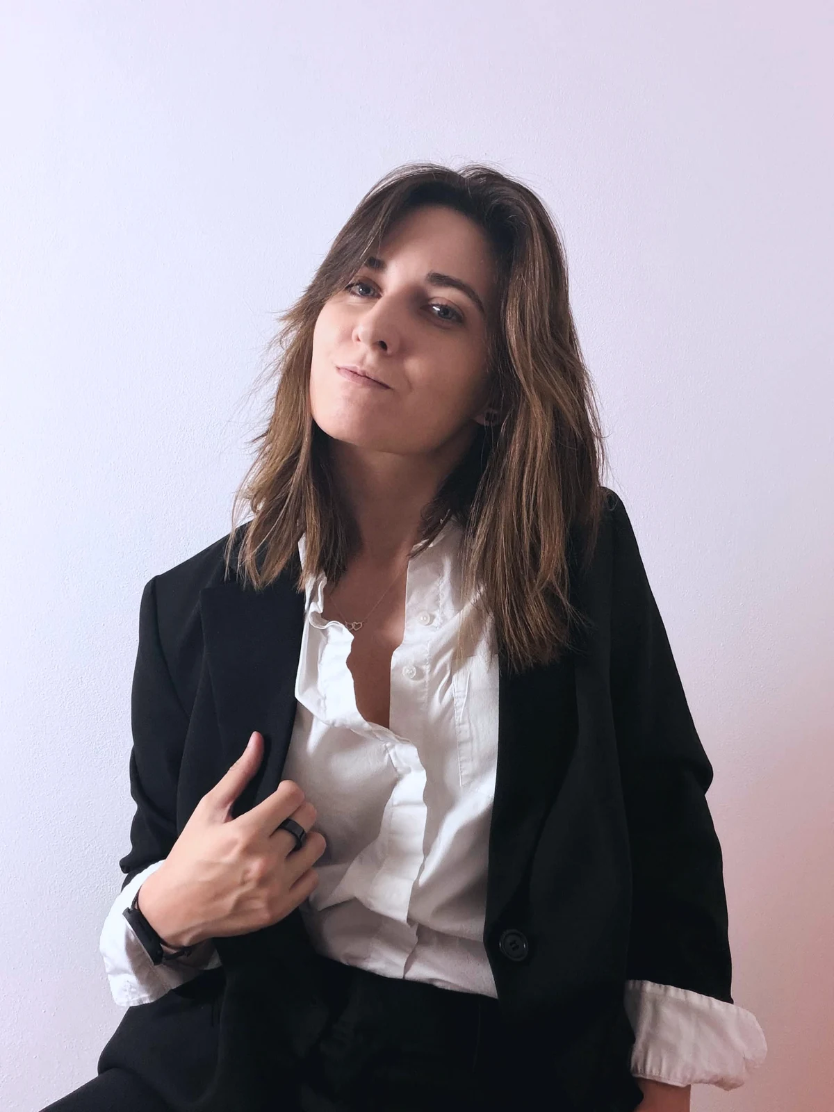 Smyxie tilting her head in a black blazer and white shirt